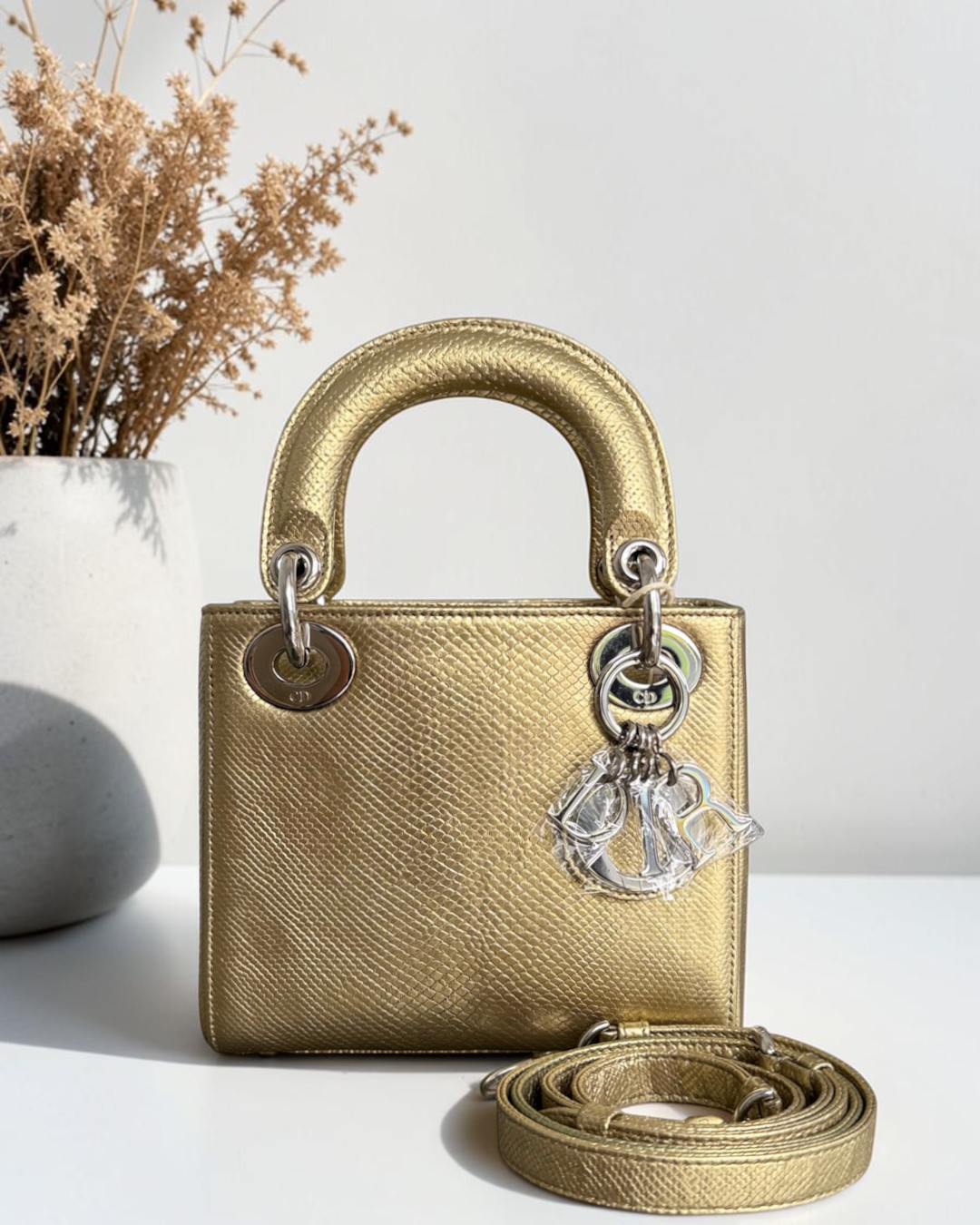 Luxury Evermore Mini Lady Dior handbag in metallic gold textured leather with silver hardware and logo charms.