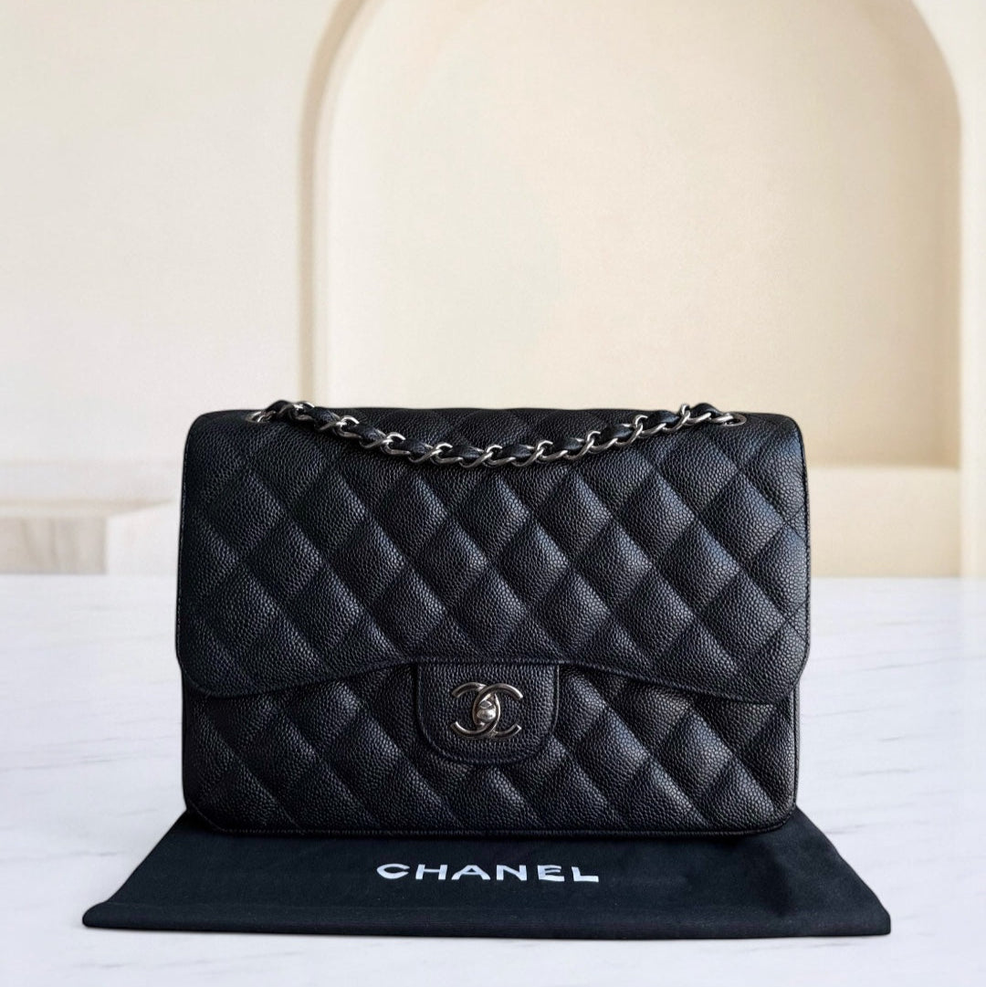 Black quilted Chanel handbag on a white surface with a neutral background