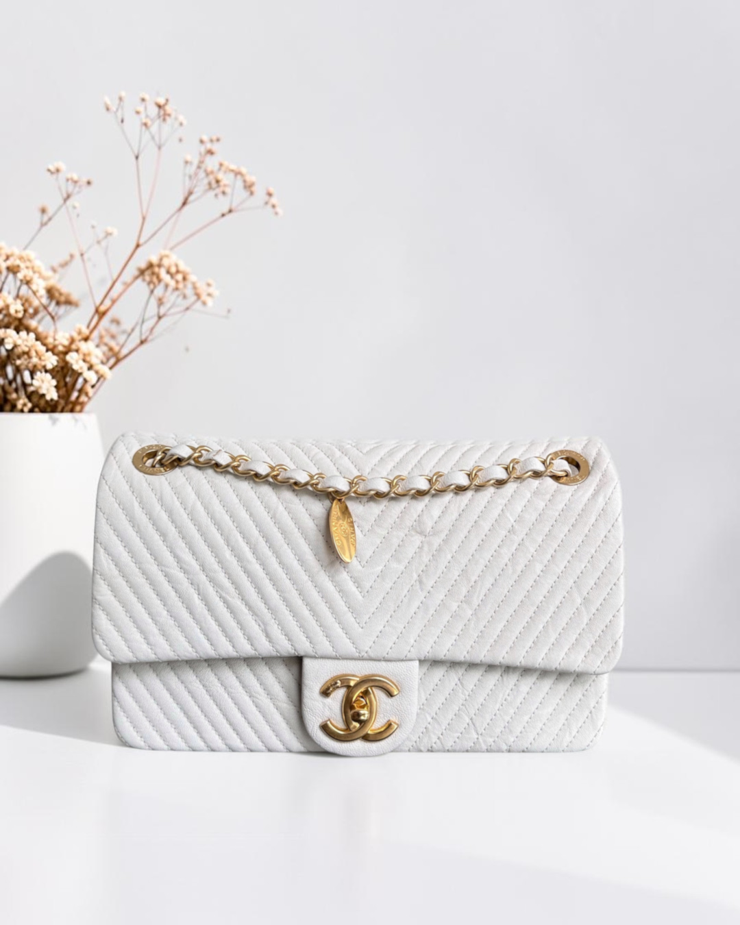 Luxury Evermore白色Chanel人字纹绗缝翻盖包，配有金色链条肩带和标志性CC锁扣及吊坠
