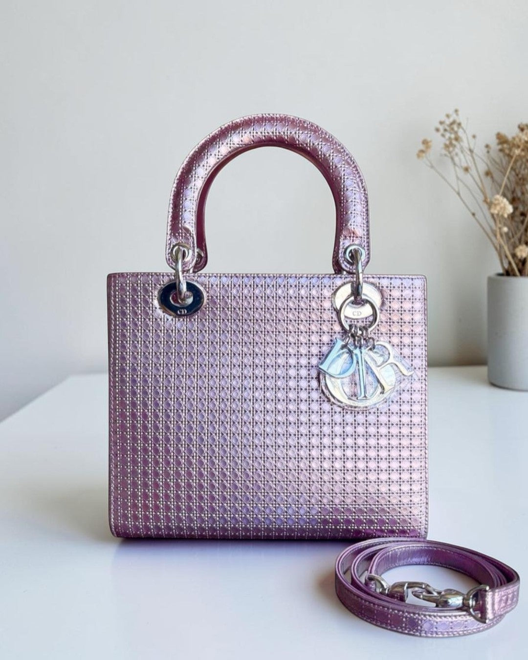 Purple handbag with a matching strap on a white surface